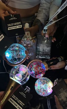 several people are gathered around an array of different colored lights and remotes on a table