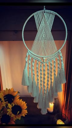 a white macrame hanging from the ceiling next to a vase with sunflowers