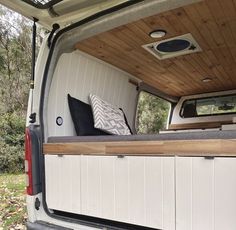 the back end of a van with its door open and pillows on it's seat