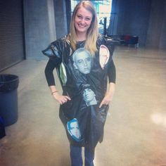 a woman standing in an empty room wearing a black shirt with pictures on the front