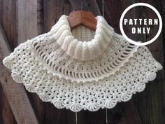 a white crocheted shawl hanging on a wooden fence with a wood hanger