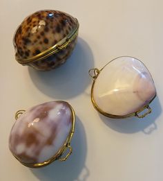 three pieces of jewelry sitting on top of a white table next to an egg shell