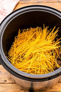 some yellow noodles are in a black pot