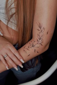 a woman's arm with a flower tattoo on her left arm and the wrist