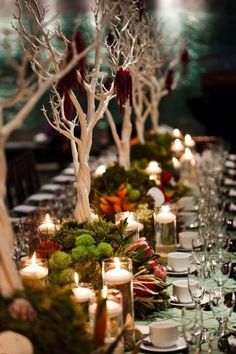 a long table with candles and moss covered trees