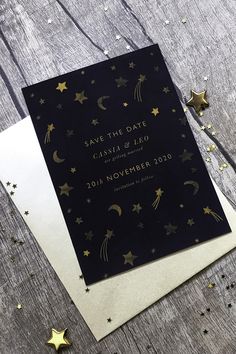 a black and gold save the date card on top of two white envelopes with stars