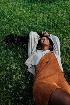 a woman laying in the grass with her eyes closed