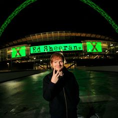 a man standing in front of a stadium at night with his hand on his face