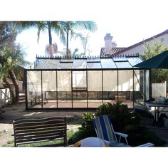 a house that has a glass wall in the front yard and lawn chairs around it