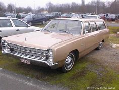 an old station wagon parked in a parking lot next to other cars and pickup trucks