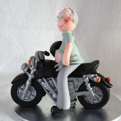 a cake shaped like an old man riding a motorcycle on a silver plate with a white background