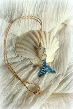 a shell with a blue tassel is laying on a white sheet and has a string attached to it