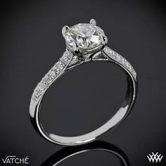 a white gold ring with an oval cut diamond in the center and pave set shoulders