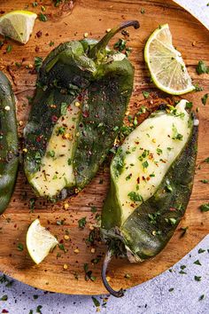 green peppers on a wooden cutting board with lemon wedges and seasoning sprinkles