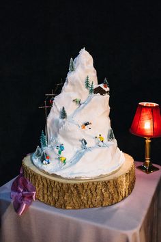 a cake with white frosting on top of a wooden table next to a lamp