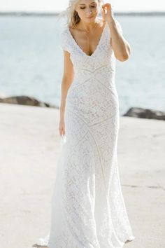 a woman in a white dress standing on the beach