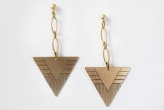 "These brass triangle dangle earrings are done with individually hand drawn, or \"scribed\", lines onto brushed and sealed brass. Brass triangles drop by way of your choice of either single or double link golden brass marquise links. All of the earrings are available in either brass fish hooks or posts! -Brushed brass is sealed to prevent tarnish. -Brass ball post and fish hook is made of surgical steel and is nickel free. Length (2 links): 2.75\" Width: 1.25\" This listing is for one of the thr Triangle Metal Earrings For Gift, Nickel Free Triangle Metal Earrings, Nickel-free Metal Triangle Earrings, Geometric Brass Earrings, Earrings Triangle, Boho Chic Earrings, Fish Hooks, Nickel Free Earrings, Chic Earrings