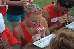 a group of people sitting at a table eating food and drinking water from plastic containers