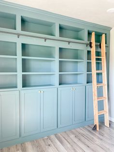 an empty room with blue bookcases and a ladder