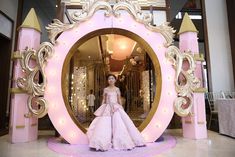 a woman standing in front of a pink and gold decorated entrance way to a store