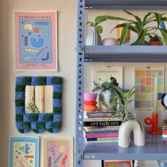 there are many books and plants on the shelves in this room, all decorated with art