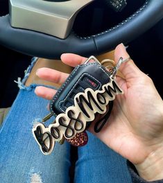 a person holding a car keychain with the word boss on it in their hand