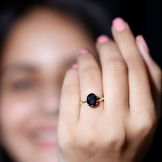 a close up of a person holding a ring with a black stone on it's middle finger