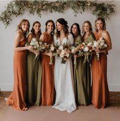 a group of women standing next to each other holding bouquets in front of a wall