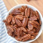 a white bowl filled with pecans on top of a wooden table