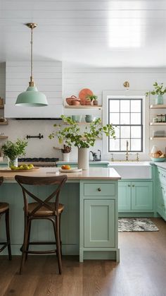 a kitchen with green cabinets and white walls, wooden flooring and an island in the middle