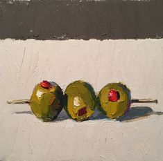 three green apples sitting on top of a white surface