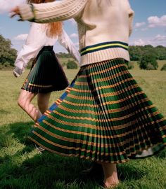 two women in skirts are standing on the grass