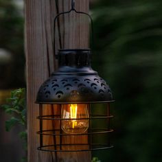 an outdoor light hanging from a wooden post