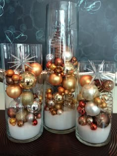 three glass vases filled with ornaments on top of a table