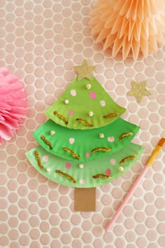 paper plate christmas tree craft for kids on a table with tissue pom poms