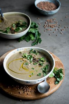 two bowls filled with soup on top of a wooden board