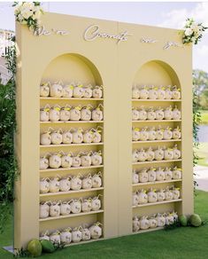 a yellow wall with two shelves filled with teapots and flowers on it's sides