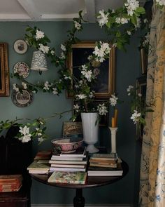 a table topped with books and flowers next to a vase filled with white flowers on top of a wooden table