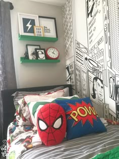 a bed with spiderman pillows on top of it in front of a wall mural