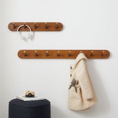 two coats hanging on the wall next to a coat rack and stool with a towel