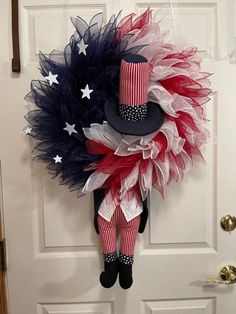 a patriotic wreath hanging on a door with an american flag hat and red white and blue tulle