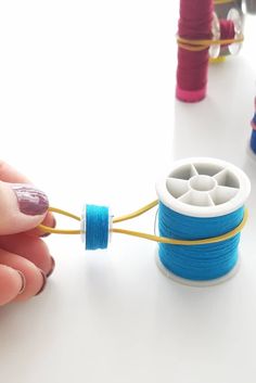 a woman is working with some thread on the table next to spools of thread