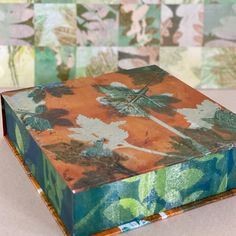 an orange and green box sitting on top of a white table next to wallpaper