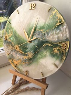 a marble clock sitting on top of a wooden stand next to a window sill