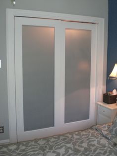 a bedroom with two sliding doors and a night stand next to the bed in front of it