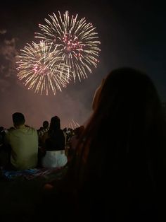 people watching fireworks in the sky at night