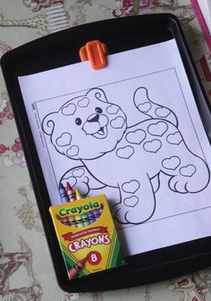 a clipboard with crayons on it and a drawing of a cartoon bear