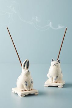 two ceramic rabbits with incense sticks in their mouths