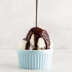 an ice cream sundae with chocolate drizzled on top, in a blue bowl