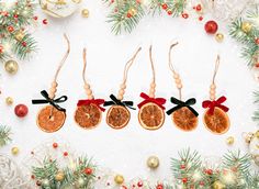 three orange slices with black bows are hanging from twine ornament on a white background surrounded by christmas decorations